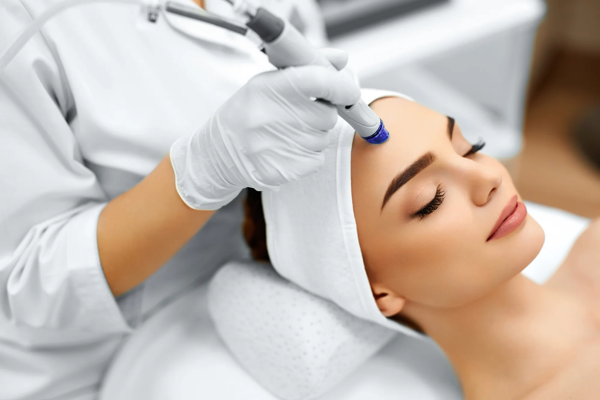 A hydradermabrasion handpiece gliding across the forehead